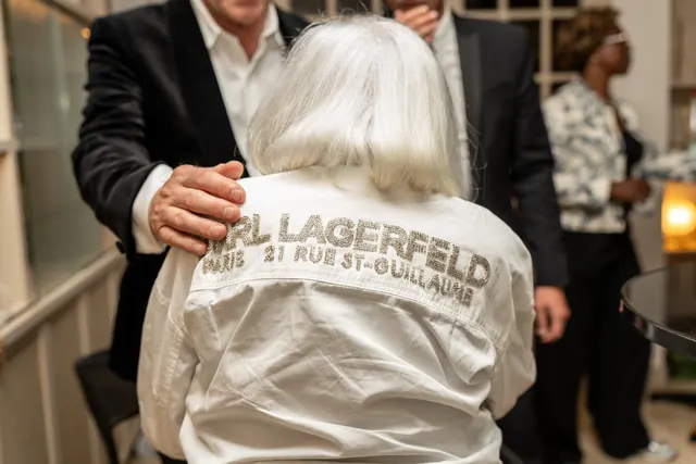 Mémé, de espaldas, con su camisa blanca de Karl Lagerfeld, abrazada por un invitado